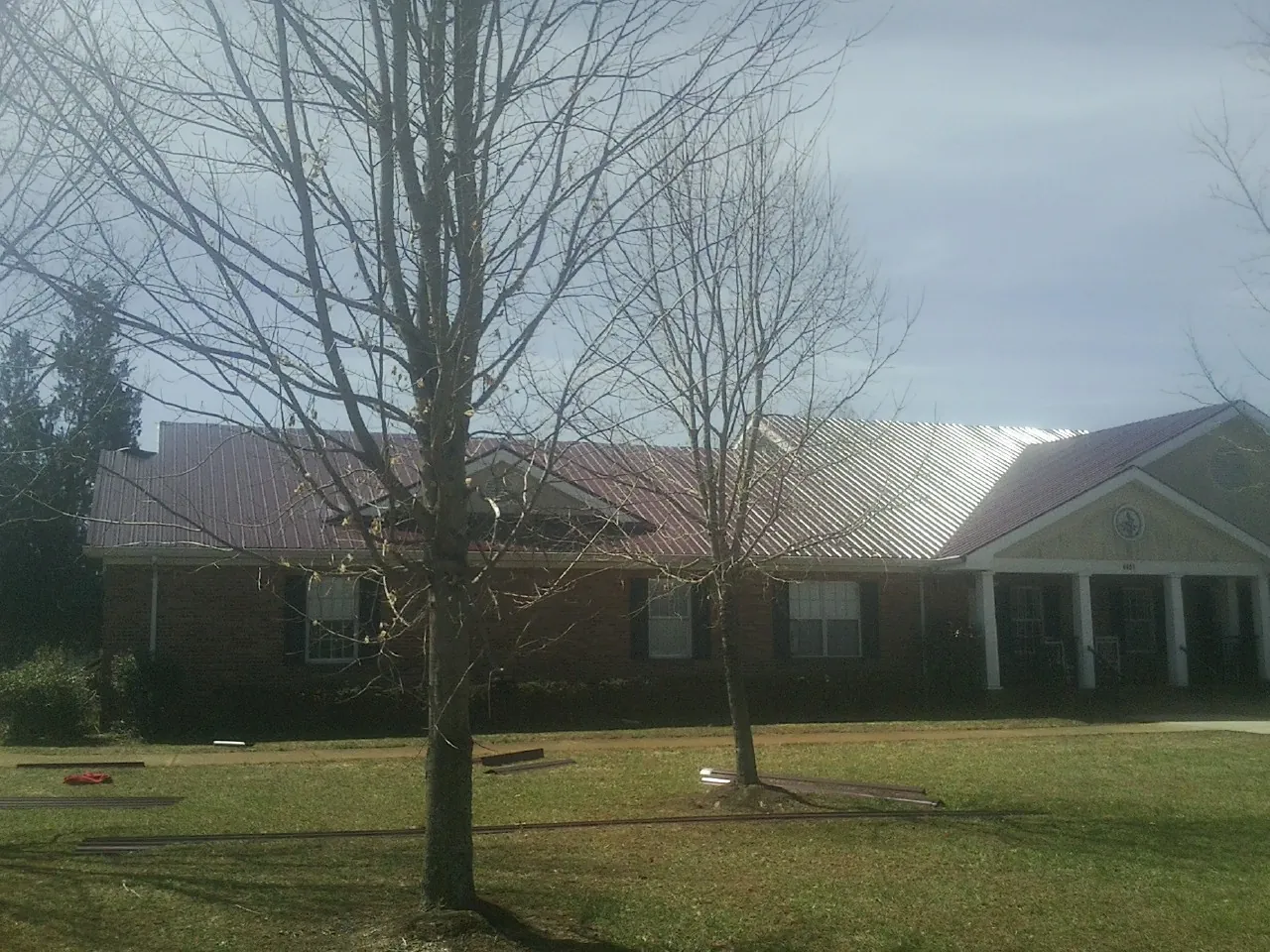 Red metal roof on a brick building seen from the front lawn in Chatham