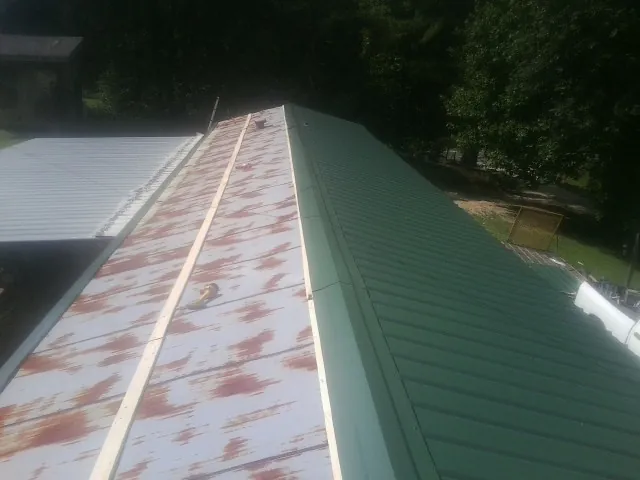 Old rusted panels beside newly installed green metal roofing — Wind Damage Roof Repair by Roofing Brothers in Chatham